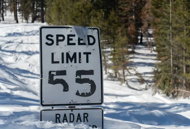 Speed limit sign in the snow, with bullet holes