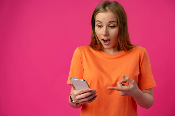 istock Excited surprised young woman using mobile phone against studio background 1372013958