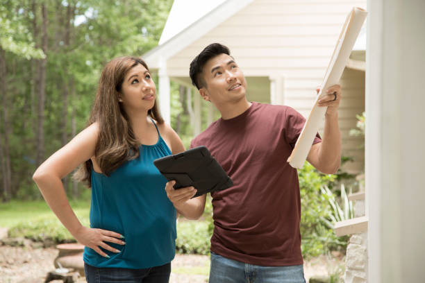 housing boom - young adults view outside of home.  they consider additions and renovations.   they have options to build or buy an already established home and do a few renovations. - building contractor engineer digital tablet construction imagens e fotografias de stock