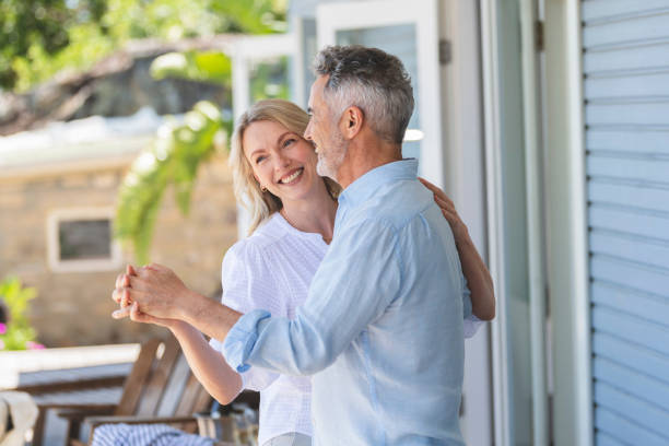Mature couple dancing at a home or holiday villa. Mature couple dancing at a home or holiday villa. They are smiling and having fun. Probably on a romantic vacation. middle aged couple dancing stock pictures, royalty-free photos & images