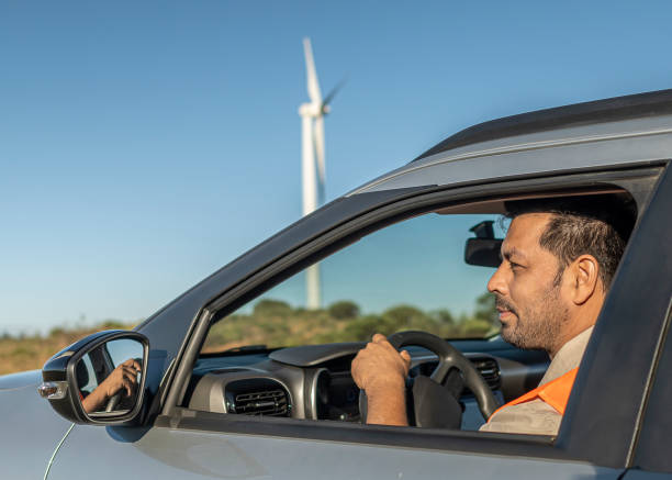 istock Electrical engineer with protective equipment in a moving car on the way to wind power plant. 1372015671