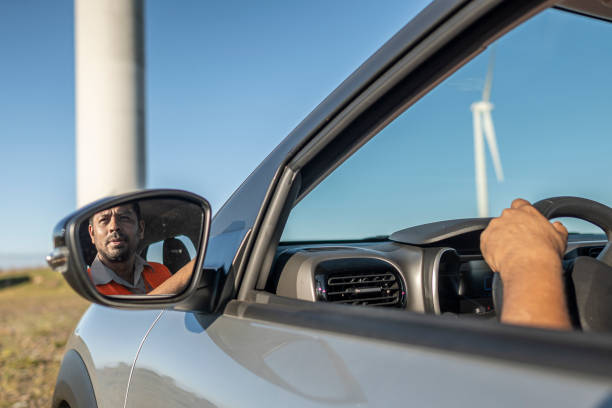 istock Electrical engineer with protective equipment in a moving car on the way to wind power plant. 1372015711