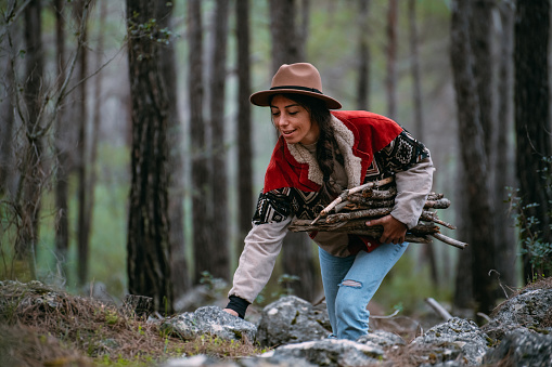 Young Woman Collects Wood for Camping in the Forest