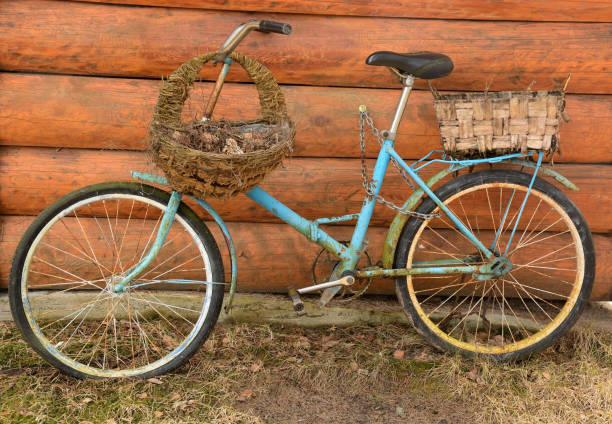 An old rusty Soviet bicycle near a wooden background with two baskets - flower beds