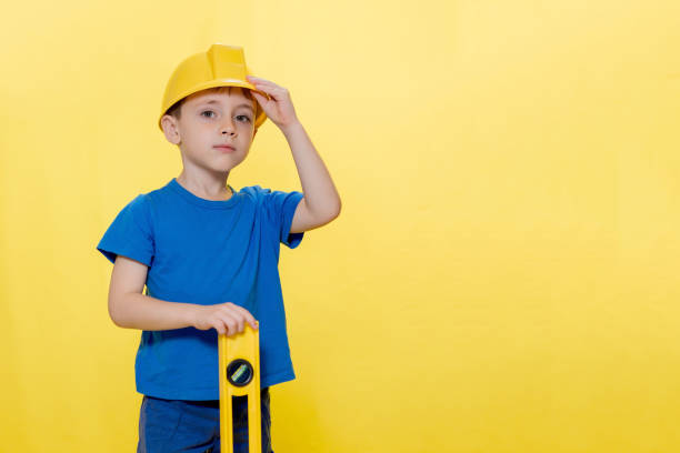 istock Little boy in yellow helmet builder with level tool 1372020679