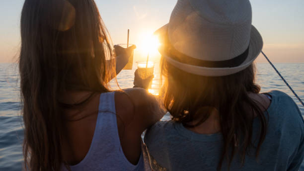 istock Two women standing on yacht with drink against romantic sunset 1372022422