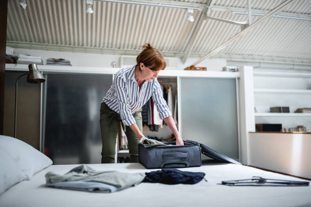 Senior woman packing suitcase for a trip stock photo