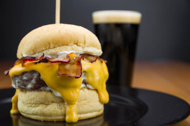 close-up of tasty homemade bacon burger and cheddar sauce - bacon cheeseburger imagens e fotografias de stock
