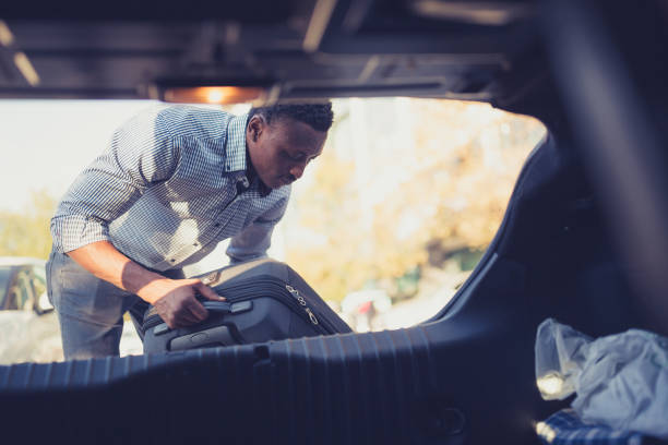 istock Young man packing a suitcase in a car trunk 1372034260