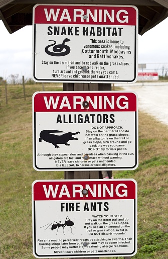 Warning sign to protect visitors of the local fauna in Florida. Signs warning visitors of the hazards from reptiles and insects as well as messaging of how to avoid the hazards. Signs at the entrance to the Viera wetlands in Florida.
