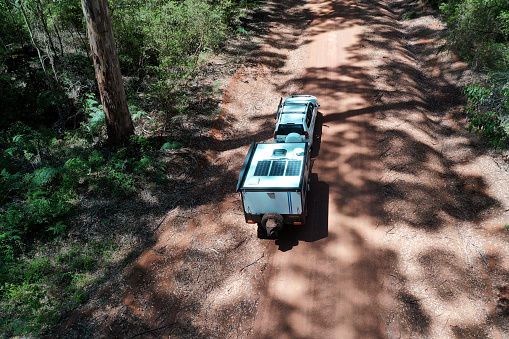 Aerial drone landscape view of off road vehicle towing a caravan in a forest in Western Australia.