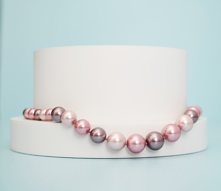 Pink and purple pearl necklace on a white plinth in a modern blue setting