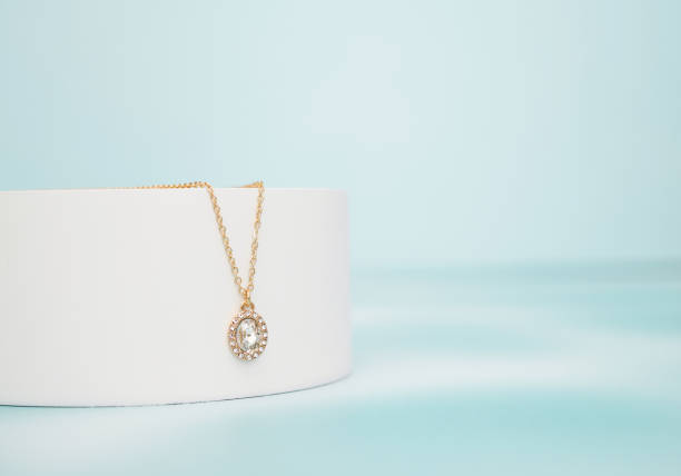 Elegancki złoty naszyjnik z mieniącą się zawieszką, idealny na ślub cywilny, wyeksponowany na białym stojaku.