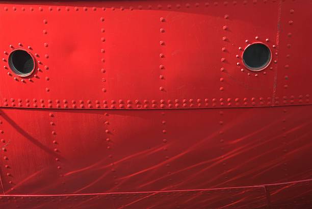 Close up of red boat hull with water reflections.