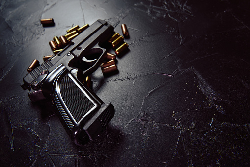 Pistola con cartuchos en mesa de concreto negro. photo