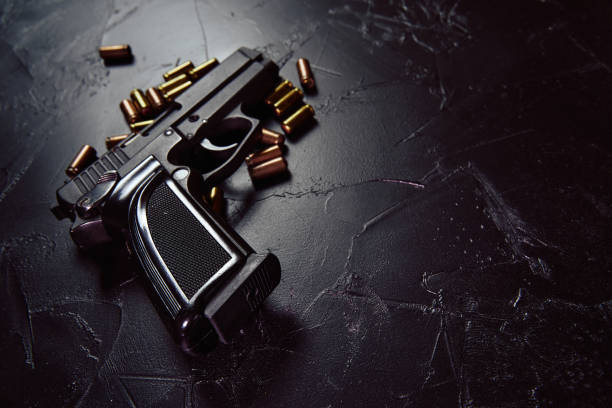 Pistol with cartridges on black concrete table. Black pistol with cartridges on table. Firearms on dark concrete table. Weapon of crime or defense. Automatic gun with bullets. Close up with copy space for text. gunman photos stock pictures, royalty-free photos & images