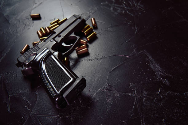 pistol with cartridges on black concrete table. - handgun imagens e fotografias de stock