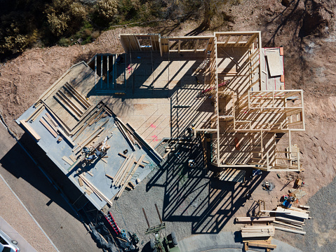 Aerial View of a home construction site with carpenter, framers working to build walls in a cul-de-sac