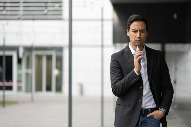 istock Asian businessman thinking while holding a smart phone 1372040949
