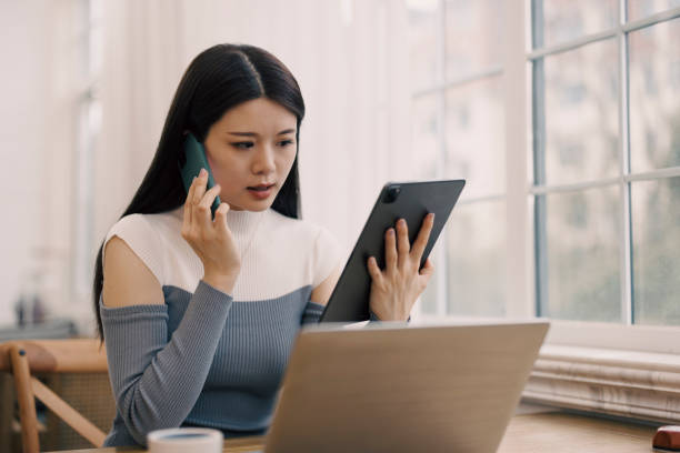 istock Young woman using tablet and calling in front of window 1372041752