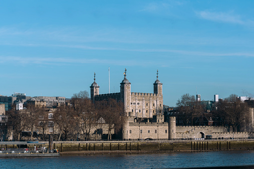 View of the Tower of London from across the Thames in the middle of the day.