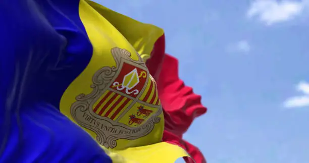 Detail of the national flag of Andorra waving in the wind on a clear day. Andorra is a sovereign landlocked microstate in Europe. Selective focus.