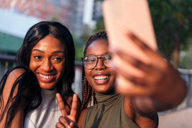 istock two funny young women smiling while taking selfie 1372047960