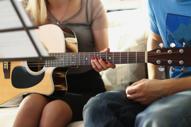 istock Female teacher explain notes to client on guitar instrument, music class at home 1372048544