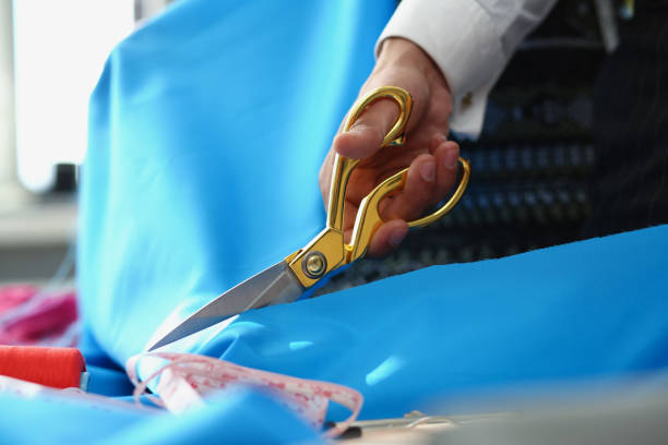 istock Person cutting blue cotton cloth with scissors tool for further sewing 1372048596