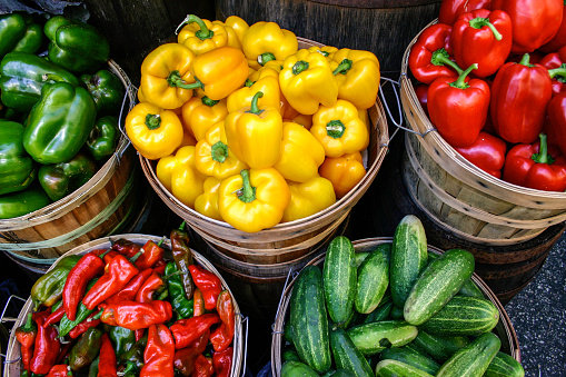 Baskets of peppers and cucumbers for sale at a farmers market