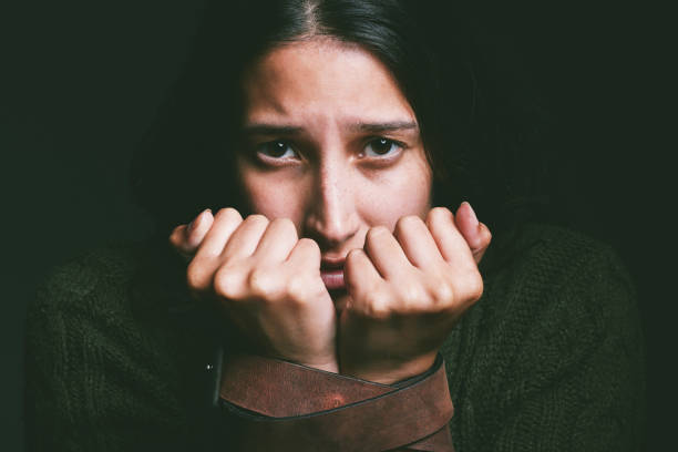 Shot of a young woman looking scared with a belt tied around her arms against a black background My mind is holding me hostage restraining device stock pictures, royalty-free photos & images