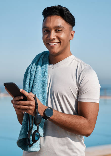 istock Shot of a young man using a smartphone before going for a swim 1372061532