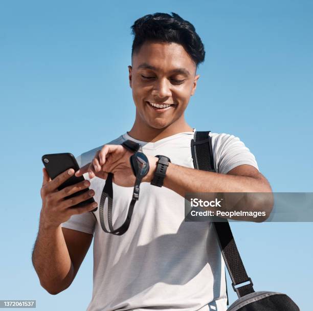 Shot Of A Young Man Looking At His Watch Before Going For A Swim Stock Photo - Download Image Now