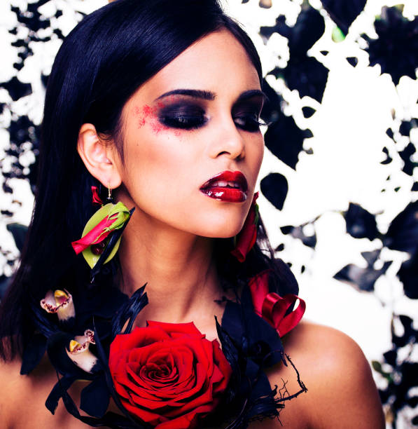 pretty brunette woman with rose jewelry, black and red, bright make up like a vampire closeup red lips stock photo