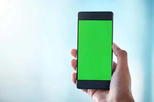 Photo of Shot of an unrecognisable person using a smartphone with a green screen on it