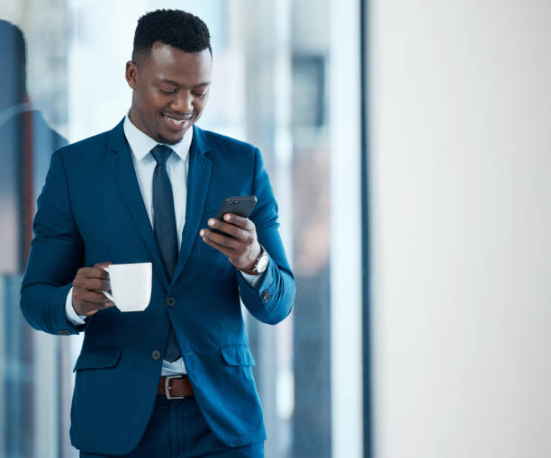 Shot of a young businessman using a smartphone in a modern office Another successful day downloaded businessman african descent on the phone business person stock pictures, royalty-free photos & images