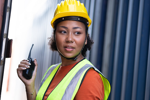 Portrait confident foreman, woman engineer use walkie talkie at container site
