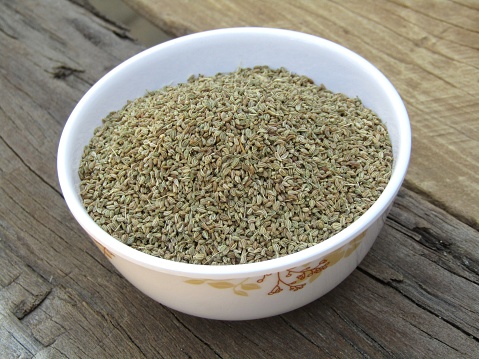 Ajwain in a bowl on a old wooden background (Trachyspermum ammi
