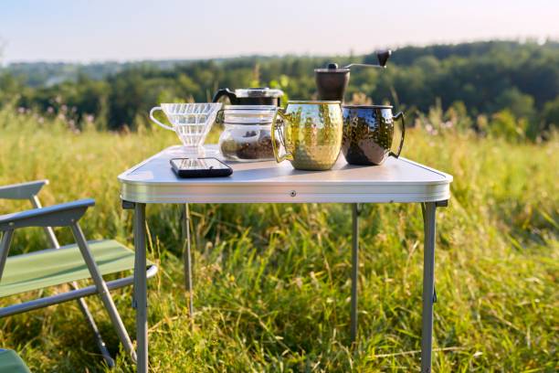Mugs, grinder, coffee beans on folding table for outdoor camping