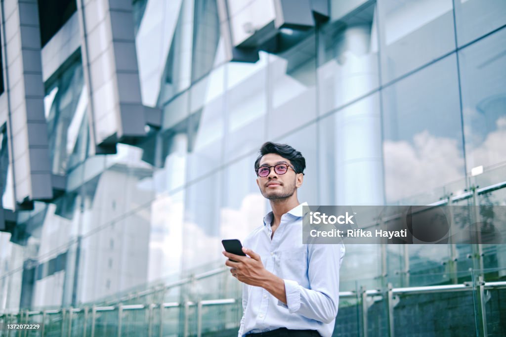 Portrait of an asian young man using mobile phone on city street City Portraits with Digital Devices Men Stock Photo