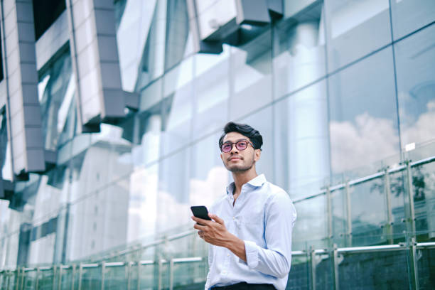 Portrait of an asian young man using mobile phone on city street City Portraits with Digital Devices indonesian ethnicity stock pictures, royalty-free photos & images