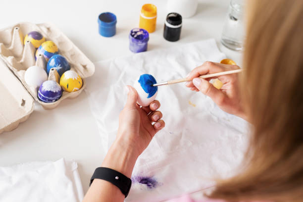 istock Woman coloring Easter eggs in the kitchen, overhead view 1372073212