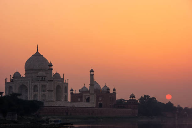Taj Mahal reflected in Yamuna river at sunset in Agra, India. It was commissioned in 1632 by the Mughal emperor Shah Jahan to house the tomb of his favourite wife Mumtaz Mahal.