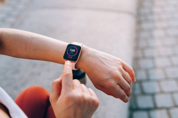 vue par-dessus l’épaule d’une jeune sportive asiatique vérifie ses statistiques de fitness sur smartwatch pour suivre ses progrès d’entraînement après s’être entraînée en ville en plein air. mode de vie actif et sain. entraînement en plein - tracker photos et images de collection