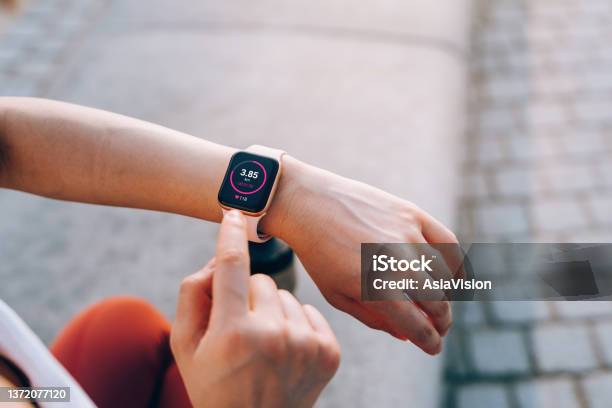 Over The Shoulder View Of Young Asian Sports Woman Checks Her Fitness Statistics On Smartwatch To Monitor Her Training Progress After Working Out In City Outdoors Active And Healthy Lifestyle Outdoor Workout Health And Fitness With Technology Concept Stock Photo - Download Image Now