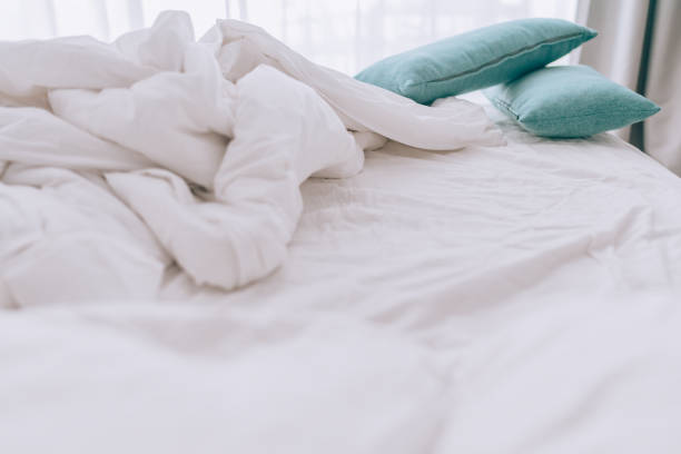 istock Unmade bed with pillows and messy white sheets 1372078235
