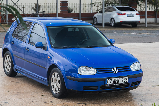 Side, Turkey -January 30, 2022:  blue Volkswagen Golf  is parked  on the street on a summer day against the backdrop of a buildung, trees, shops