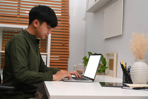 istock Side view handsome asian man working online with laptop at home office. 1372081128