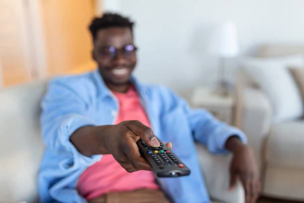 istock Excited African American Man Pointing Television Controller To Camera Switching Channels Watching TV . Television Programming Advertisement. Selective Focus 1372081420