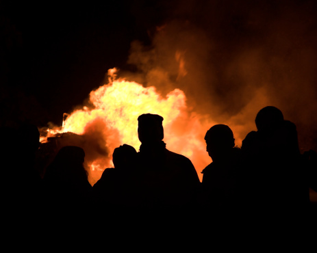 Silhouetted people around a bonfire at night